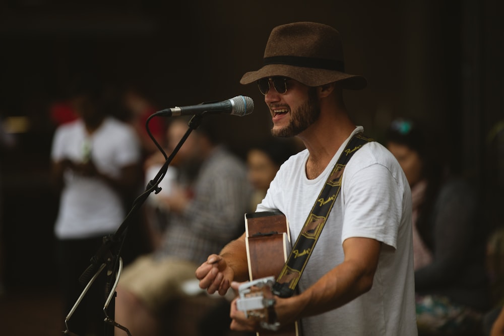 selective focus photography of man playing guitar and using microphone