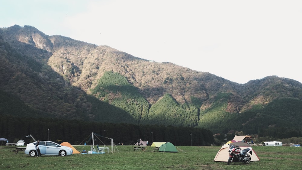 昼間は白い雲の下の山の近くにある色とりどりのドームテント