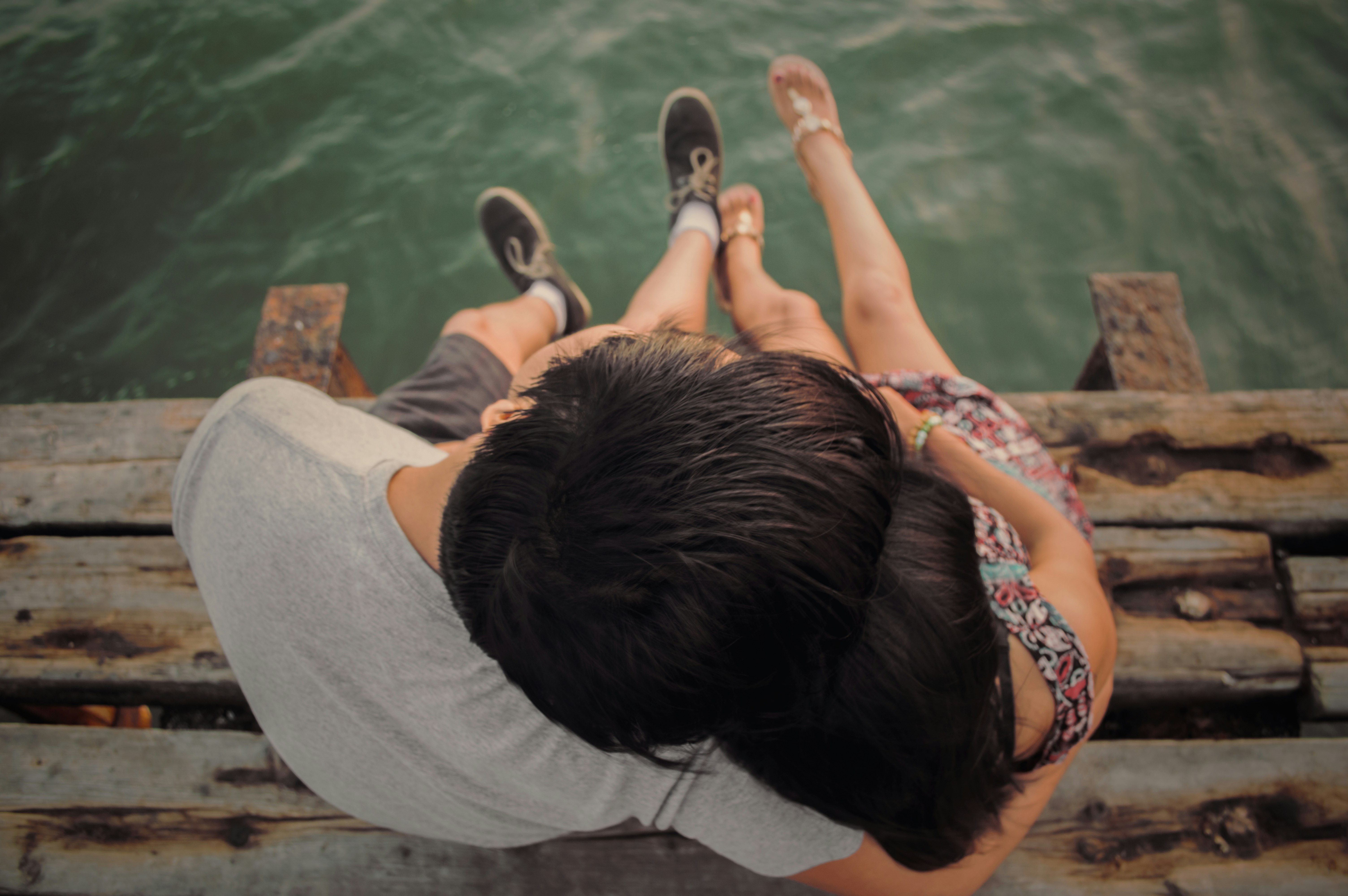 man and woman hugging each other on brown wooden dock