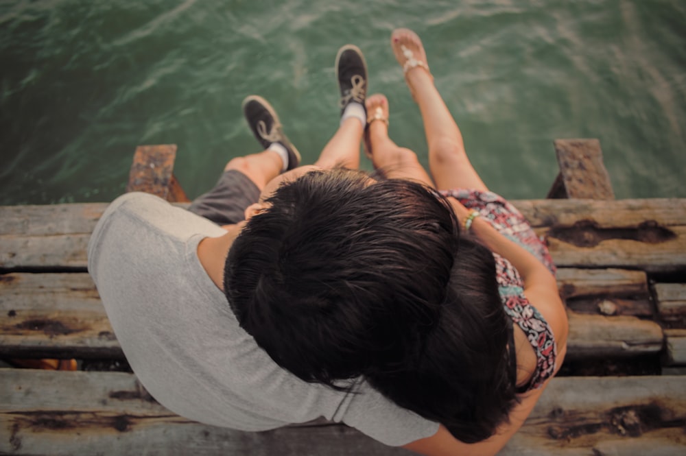 man and woman hugging each other on brown wooden dock