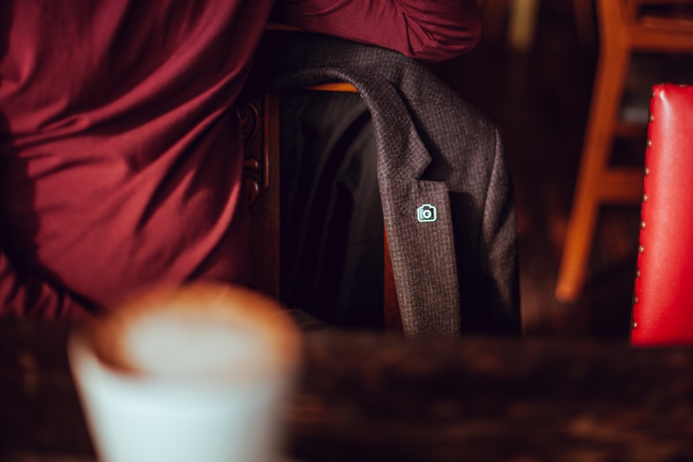 A blazer with an Unsplash pin, hanging on a chair at a cafe table