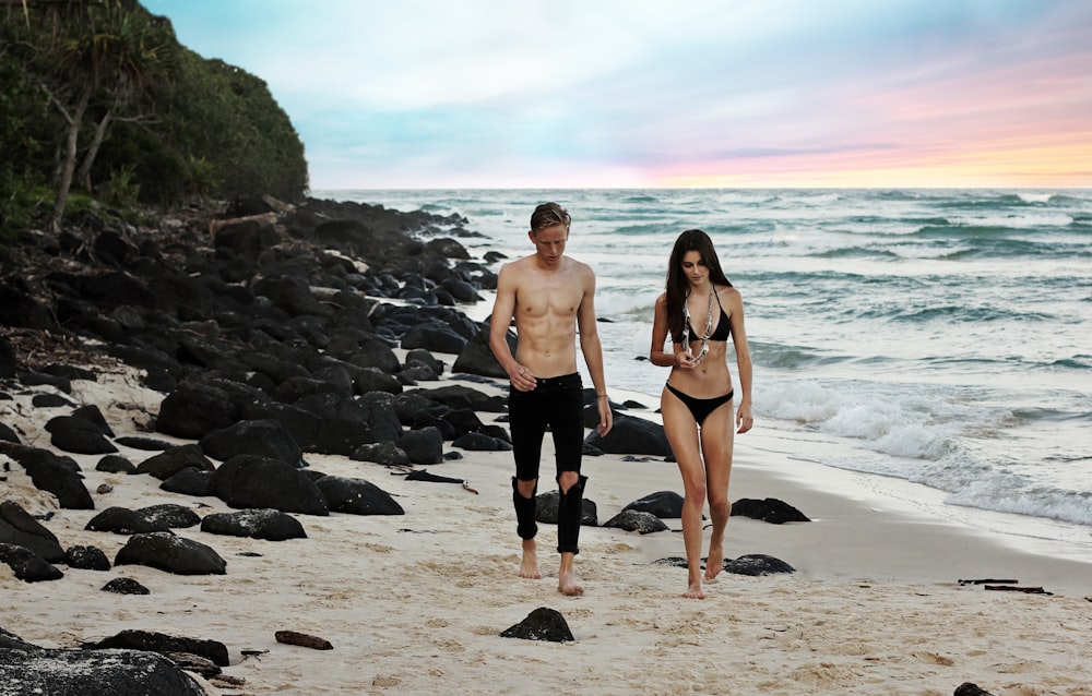 man and woman walking beside body of water