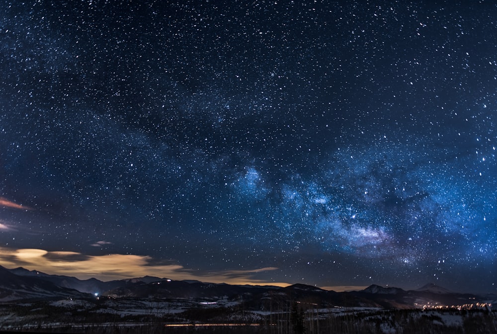 夜の白い星の下に木々が生い茂る山々