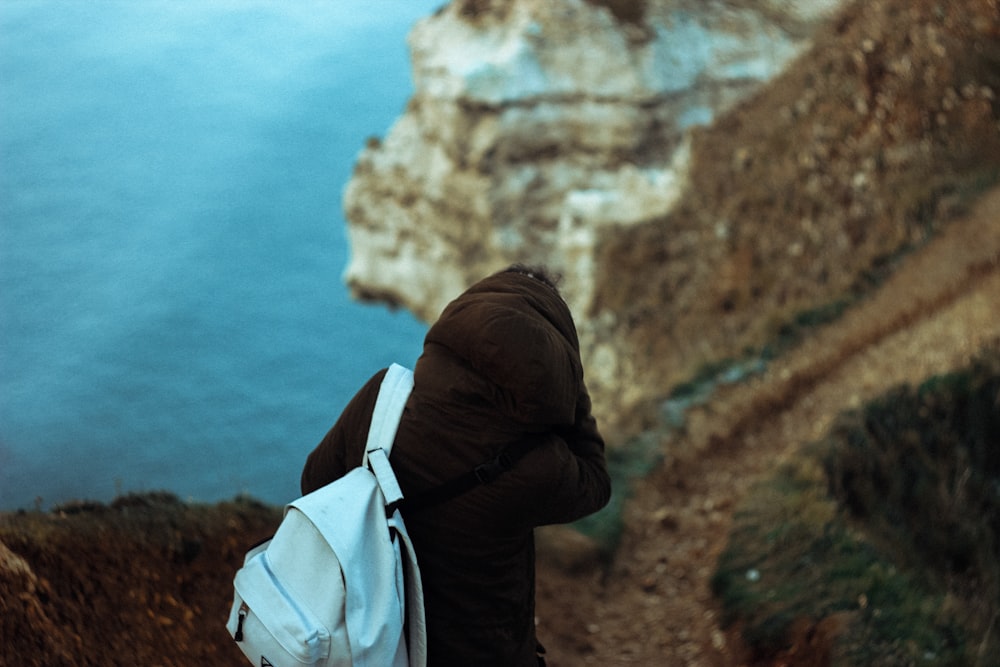 person with blue backpack near body of water