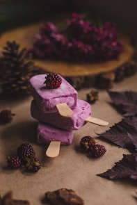 selective focus photography of thee purple ice pops near pine cones