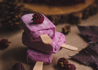 selective focus photography of thee purple ice pops near pine cones