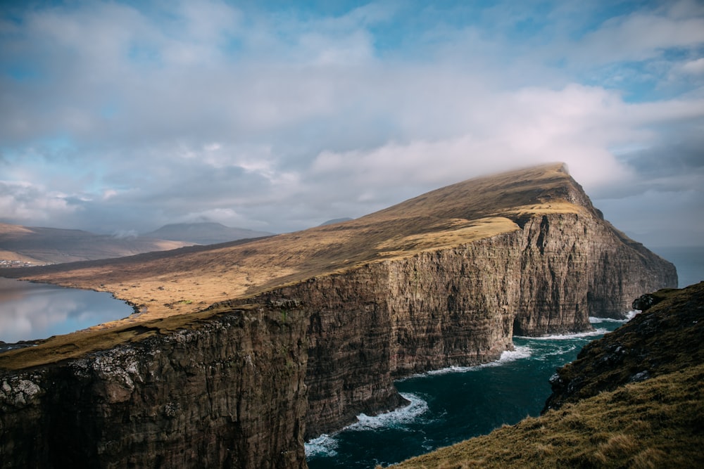 brown cliff near body of water under eblue sky