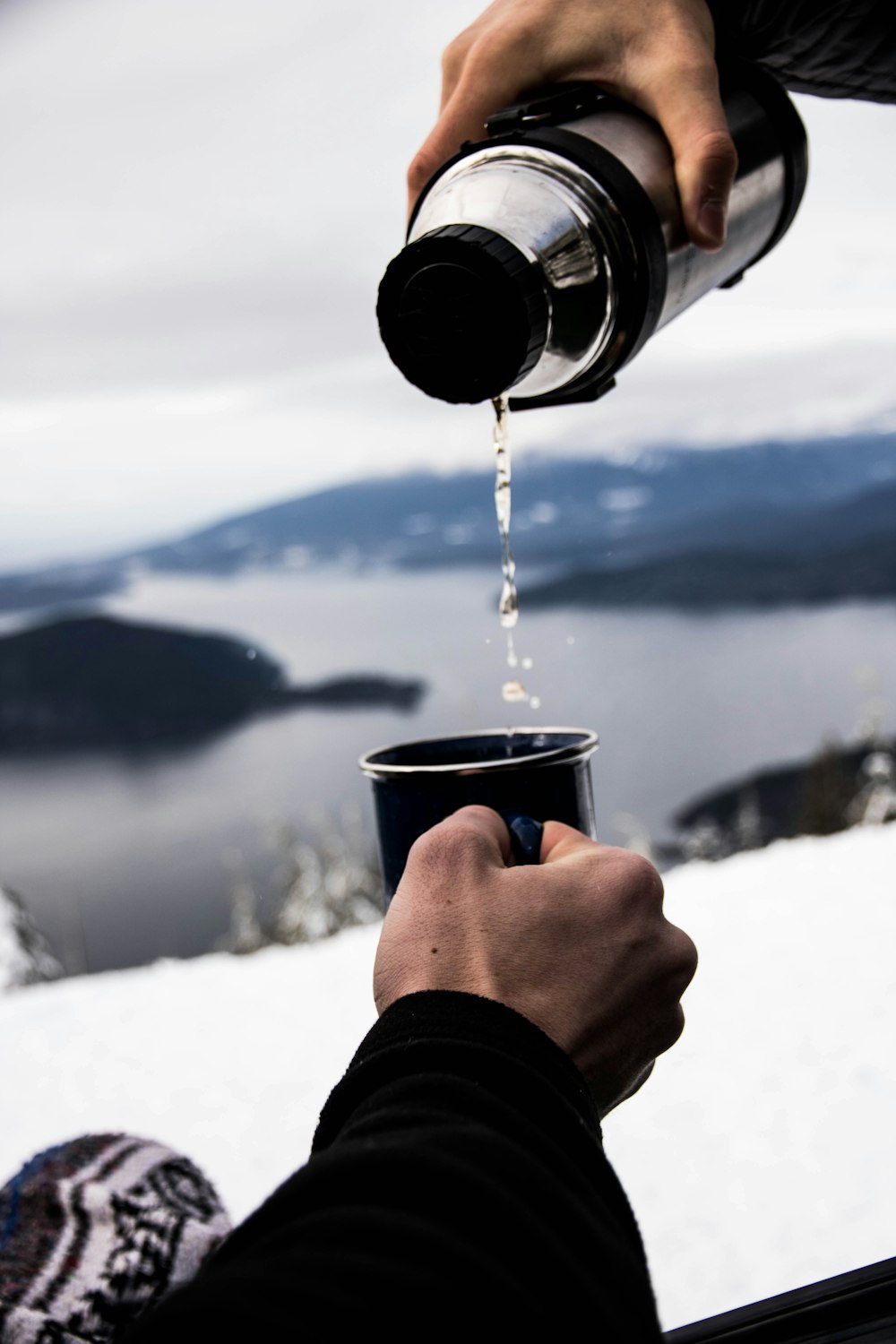 黒い陶器のマグカップに水を注ぐ人