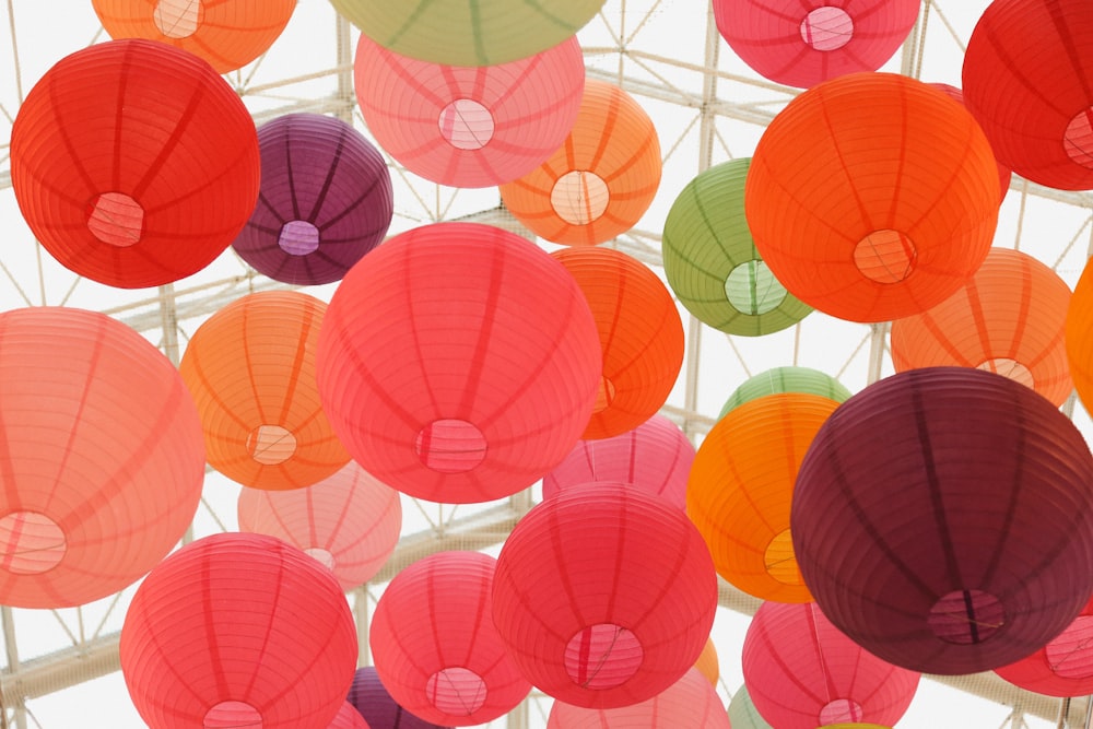 Large round colorful balloons floating to the roof of a glass house.