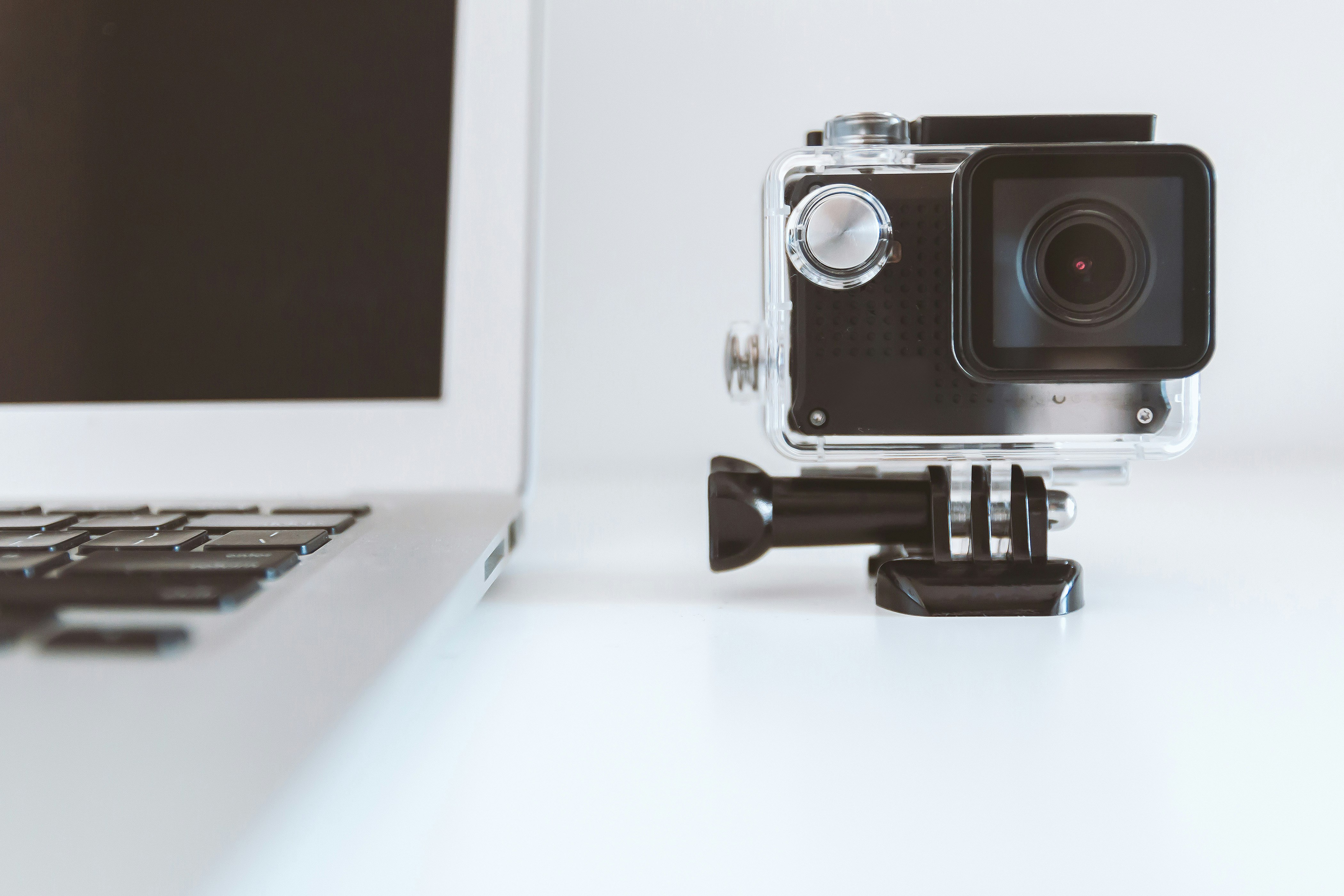 black action camera beside white laptop