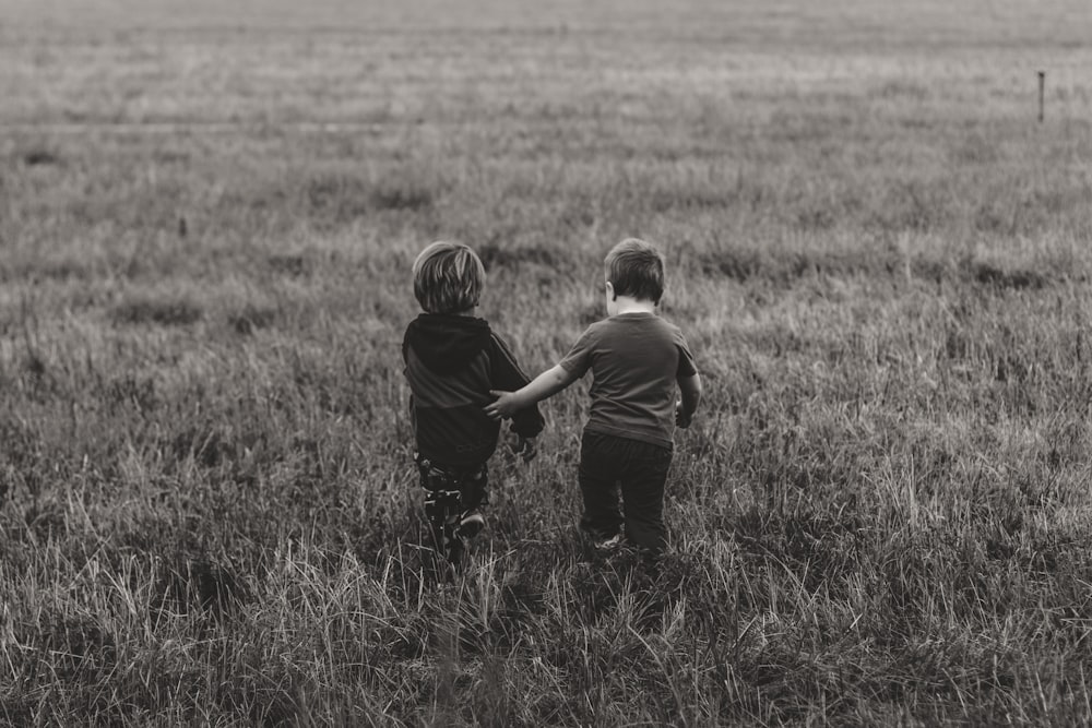 dois meninos andando em campo de grama verde