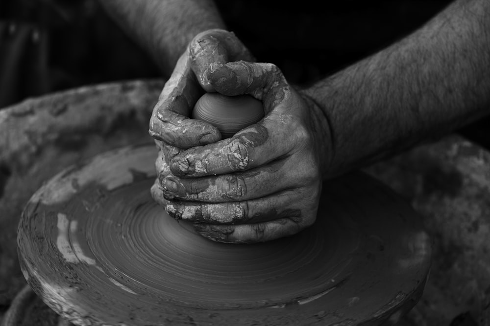 grayscale photography of person's hand making pot