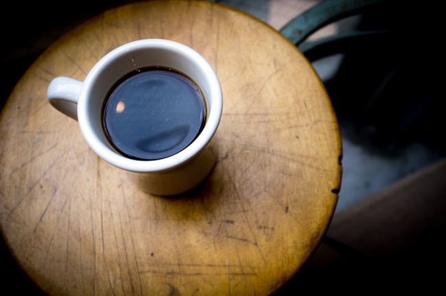 A cozy morning scene with a ceramic cup filled with steaming coffee on a wooden table.