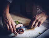 Hands carefully cleaning and preparing octopus on a wooden table.