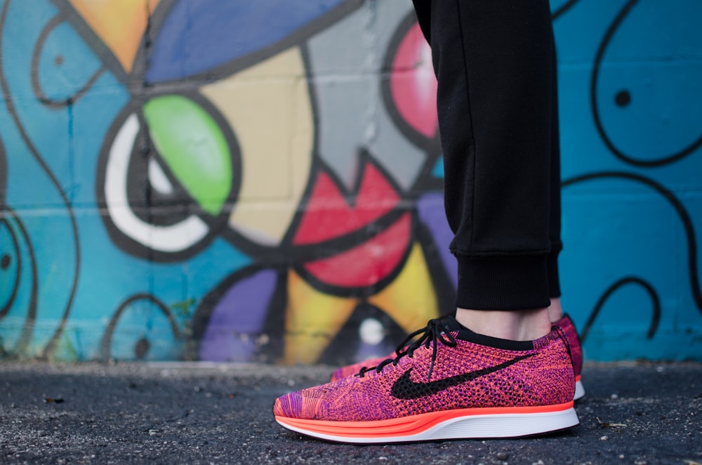 Person zeigt ein Paar pinkfarbene Nike Low-Top-Turnschuhe