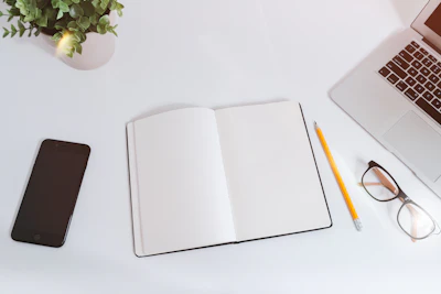 Clean desk with an open notebook, phone and laptop, ready to begin