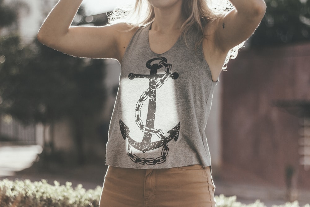 woman wearing gray tank top and brown bottoms lifting her hands upward