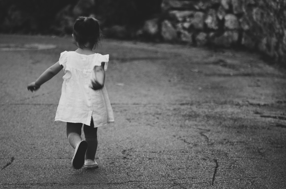 fotografia em escala de cinza da menina que caminha em direção ao destino