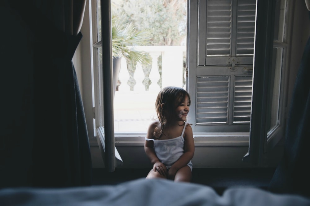 girl sitting by the window during daytime