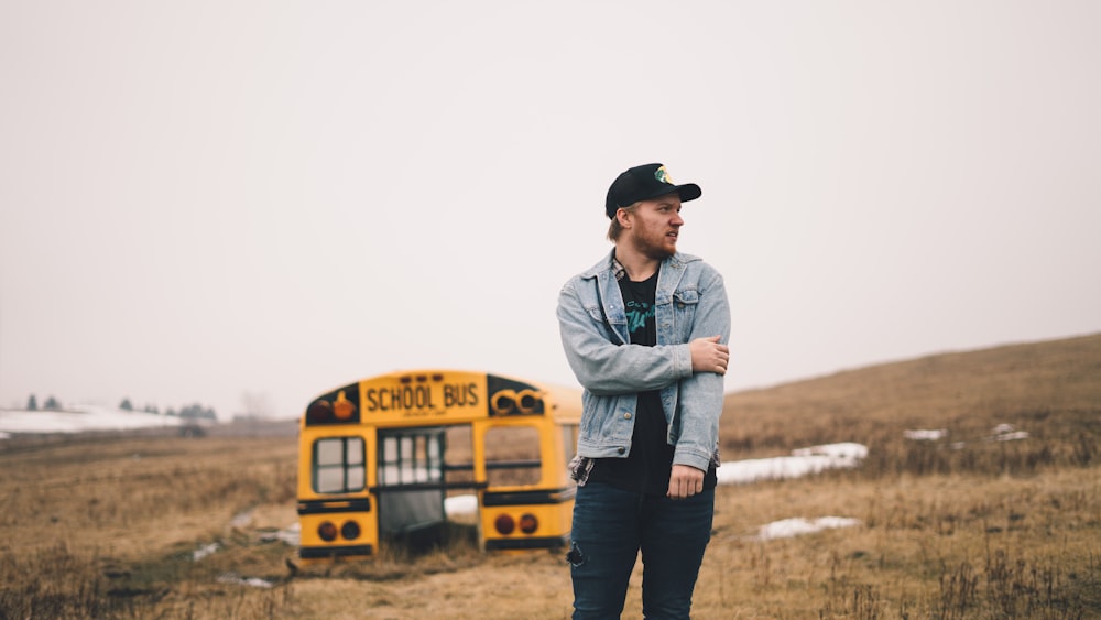 man standing on grass field near school bus part during daytime