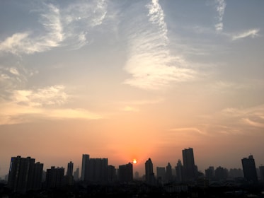 Evening city skyline glowing softly under a pastel sky.