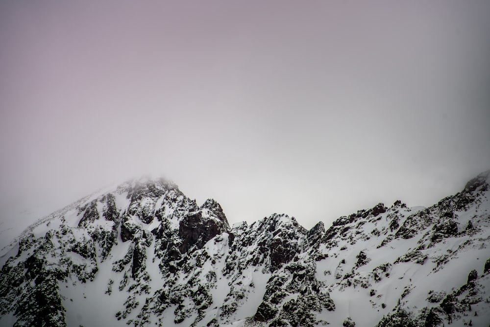 montanha coberta de neve sob céu nublado cinza