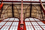 Large arched windows with a steel framework and a grid-patterned glass ceiling, featuring a combination of geometric shapes and industrial design elements.