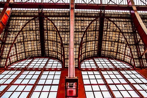 Large arched windows with a steel framework and a grid-patterned glass ceiling, featuring a combination of geometric shapes and industrial design elements.