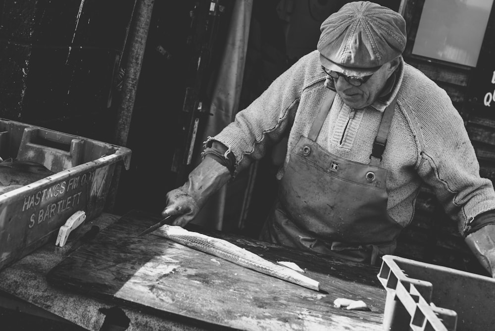homem segurando faca cortando substância branca em tábua de madeira marrom