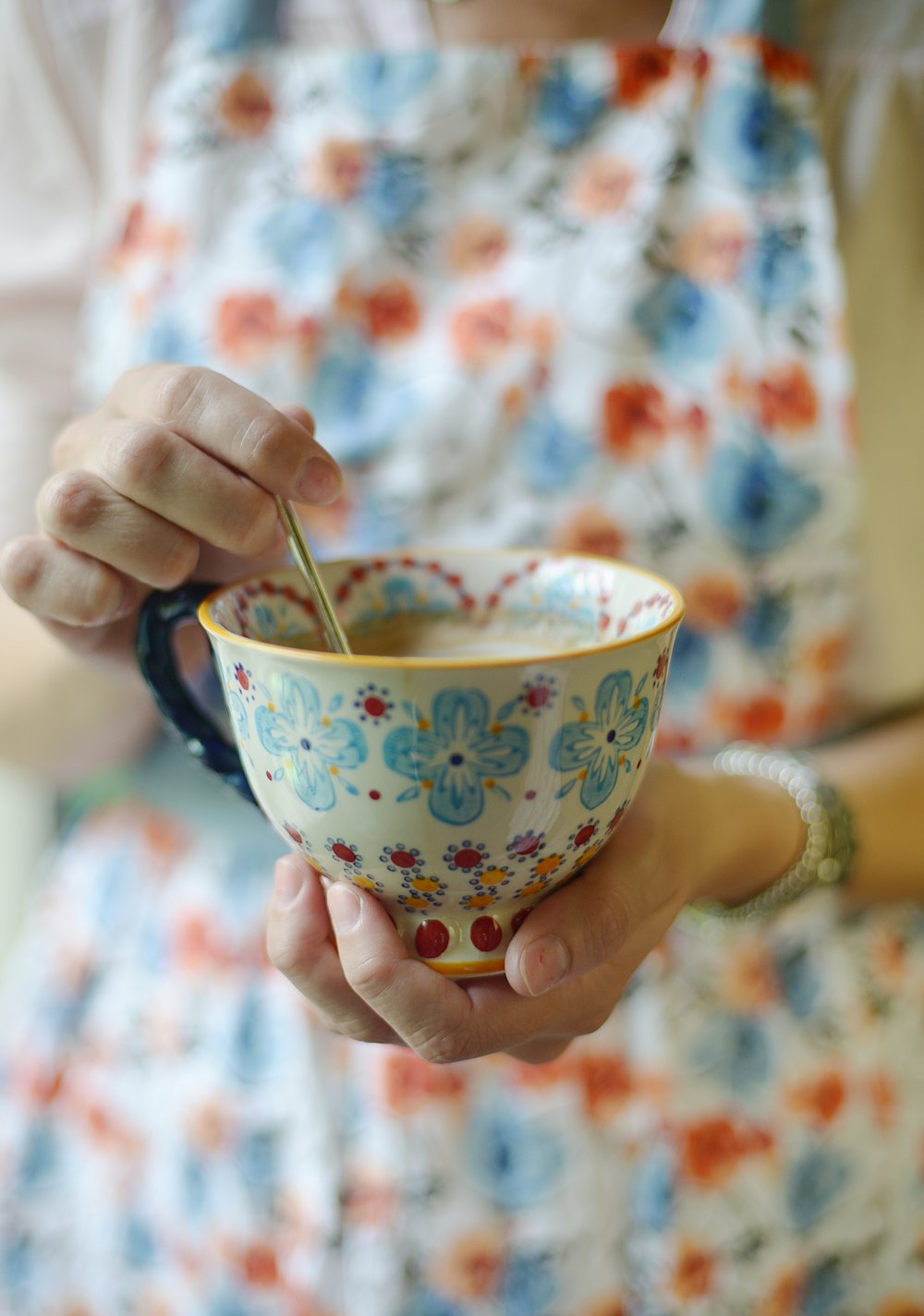 personne tenant une tasse à thé en céramique multicolore