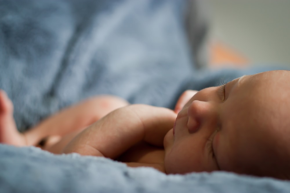 closeup photo of baby on blue blanket