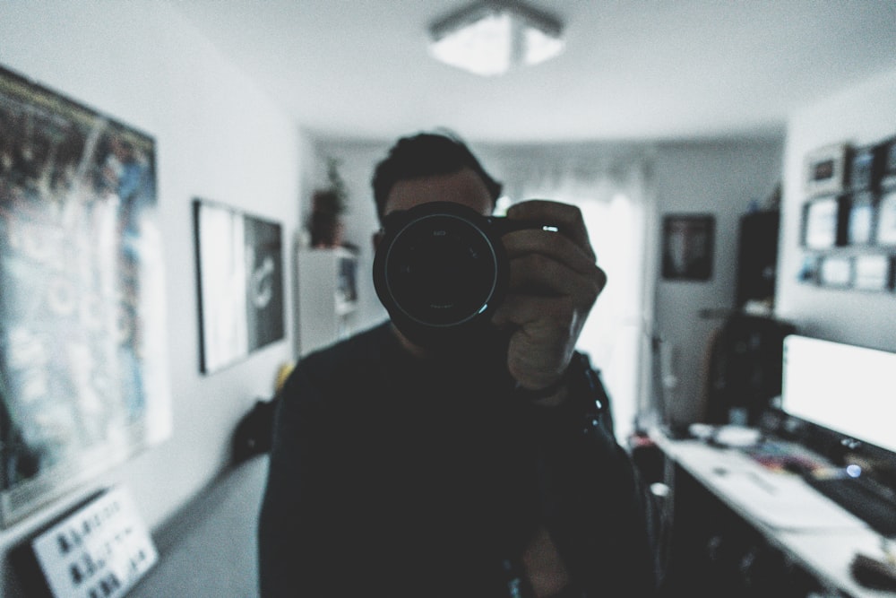 person holding camera inside white painted room