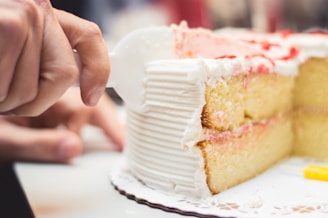 A close-up of hands cutting a beautifully decorated cake at an event.