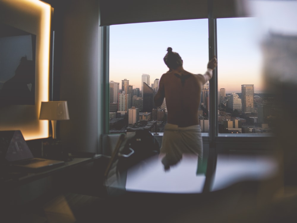 man standing beside window during daytime