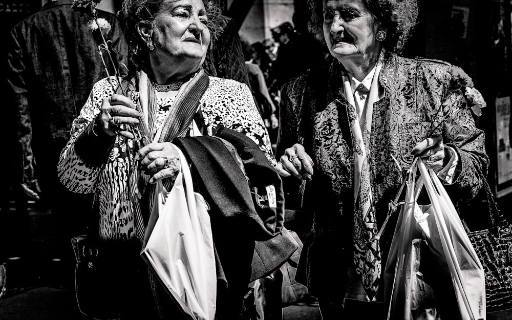 foto em tons de cinza de duas mulheres segurando sacos