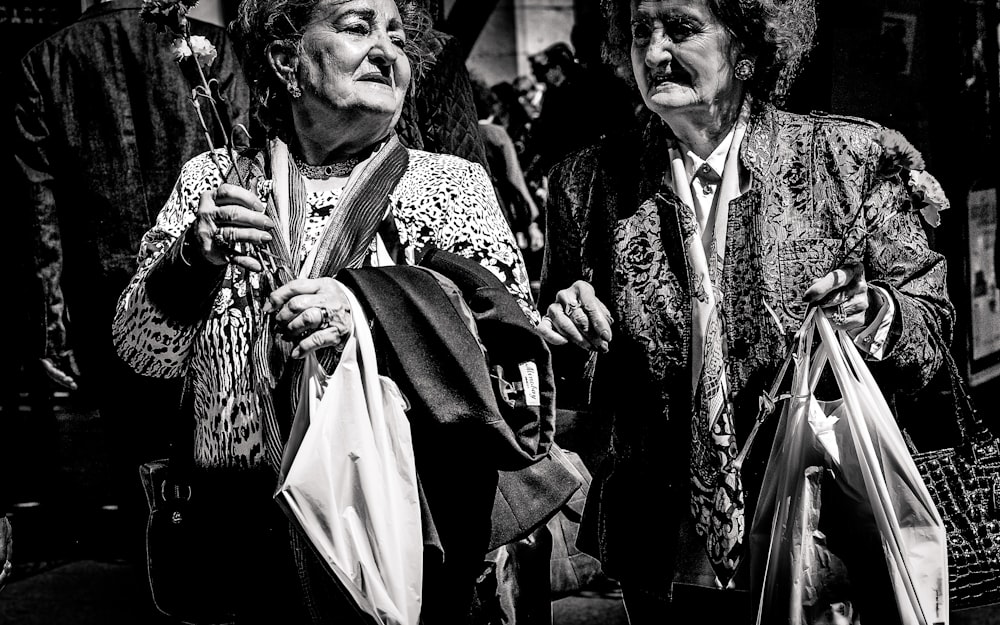 Photo en niveaux de gris de deux femmes tenant des sacs