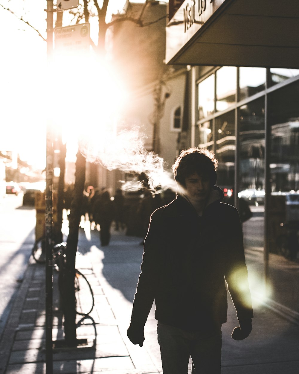 man walking on sidewalk beside glass wall