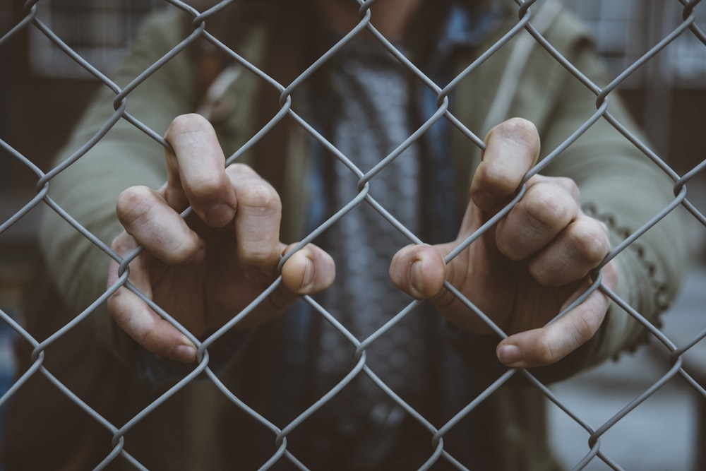 person behind mesh fence