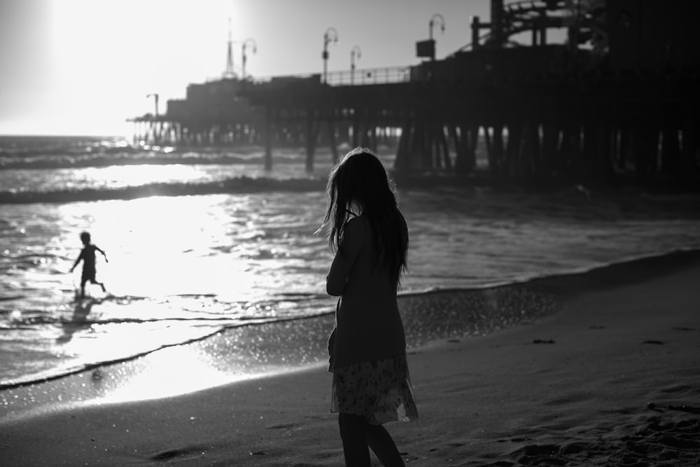 grayscale photography of woman standing in beach