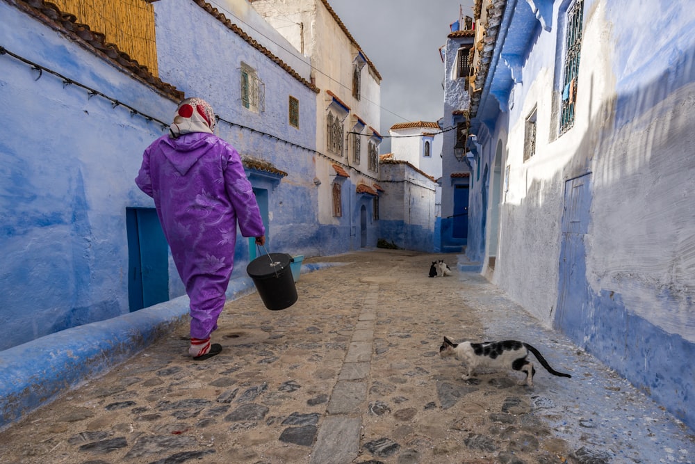 femme marchant dans la rue avec un chat à côté de la maison