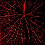 A pattern resembling a cracked surface with red fissures spreading outwards on a black background. The cracks are irregular and create a web-like appearance.