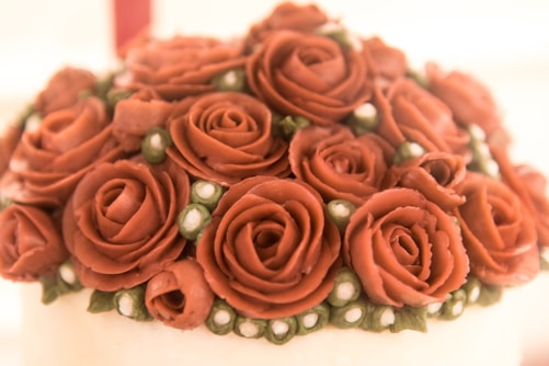 A close-up of hands skillfully decorating a colorful cake with delicate icing flowers.