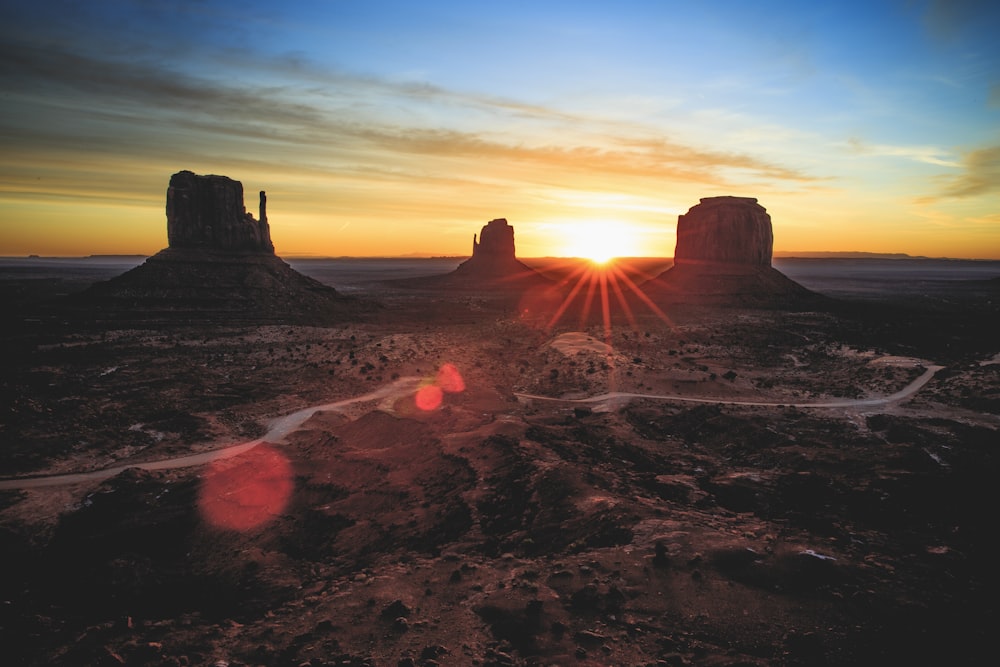 the sun is setting over a desert landscape