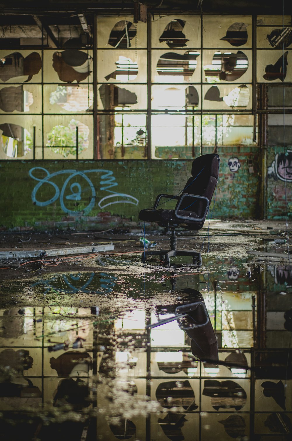 廃墟となった建物にある黒い転がる肘掛け椅子の写真
