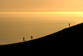 three persons running downhill during golden hour
