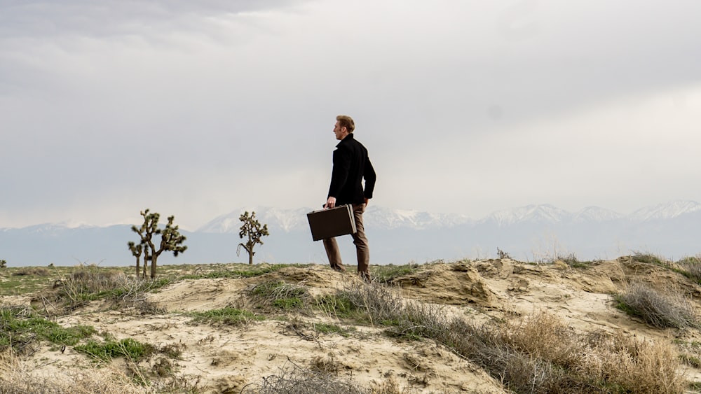 An elegantly dressed man with a suitcase in the wilderness