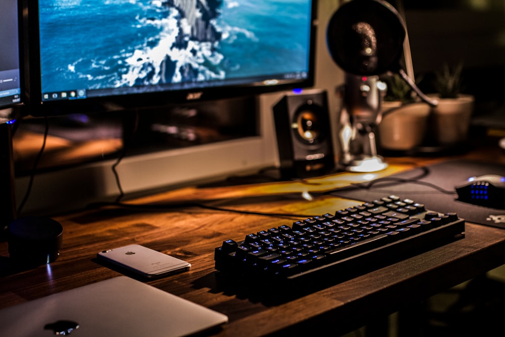 A blurry shot of a computer workspace with a backlit keyboard, a laptop and a smartphone