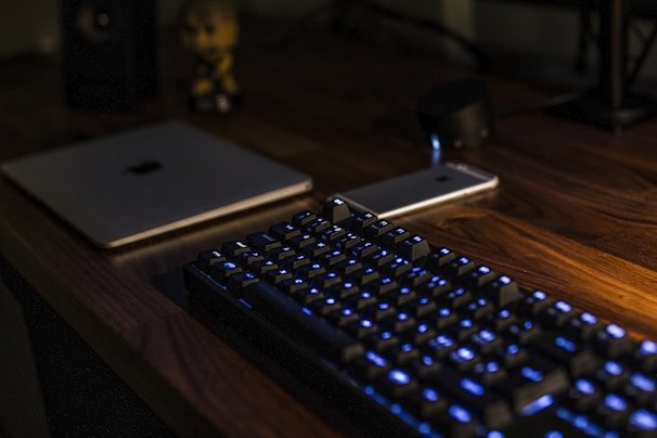 A sleek laptop and smartphone setup on a modern desk with ambient lighting