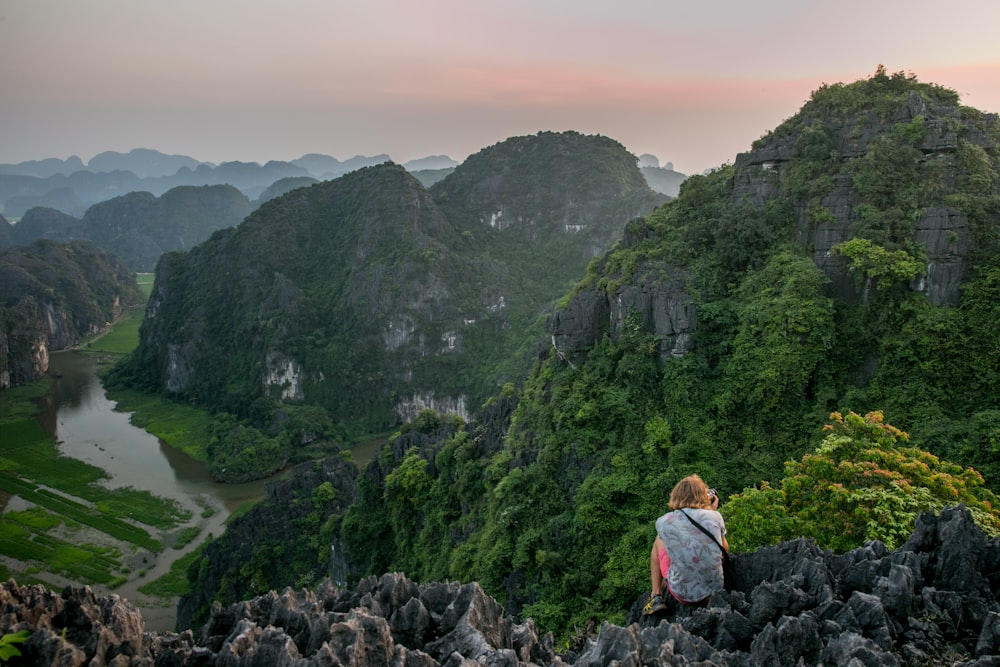 person sitting on cliff during daytime