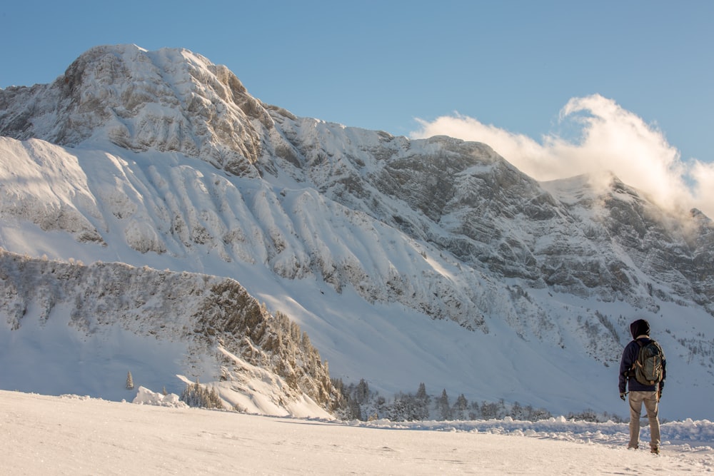 hombre frente a la montaña cubierta de nieve